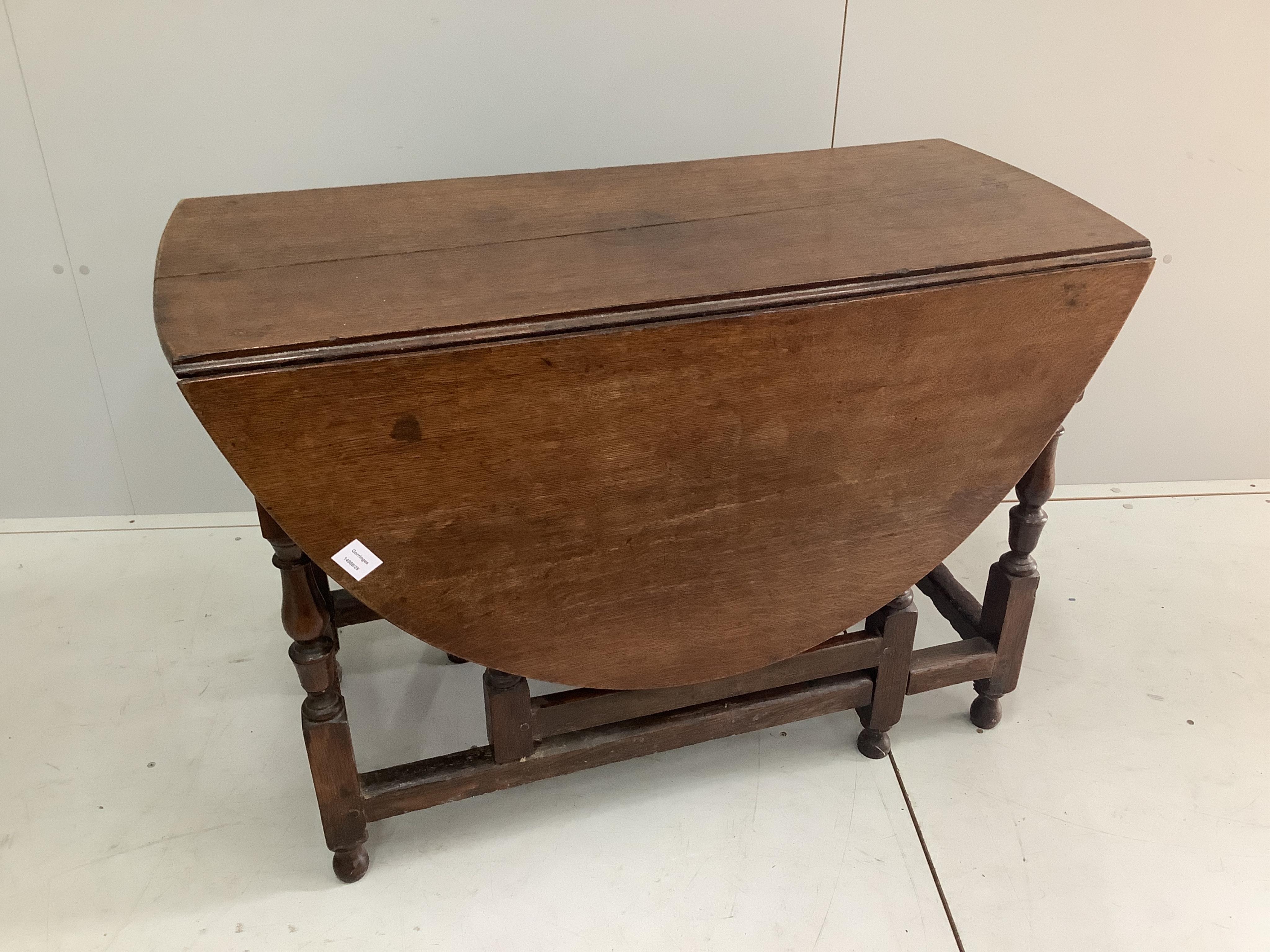 An early 18th century oak oval topped gateleg dining table, fitted with a drawer, width 104cm, depth 47cm, height 73cm. Condition - fair